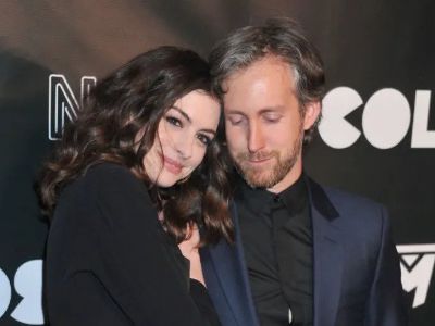 Anne Hathaway is leaning onto Adam Shulman in the picture as they are getting pictures clicked at an event.